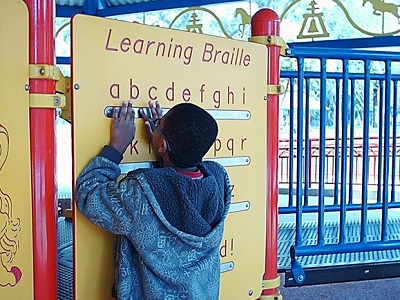 a teen touches the Braille Wall with his fingers